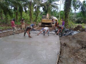 Tak Mau Ketinggalan, Wakapolsek Bangun Purba Ikut Ngecor Jalan TMMD Kodim 0204/DS